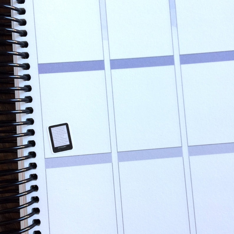 May include: A white planner with a black and white sticker of an e-reader on the page.