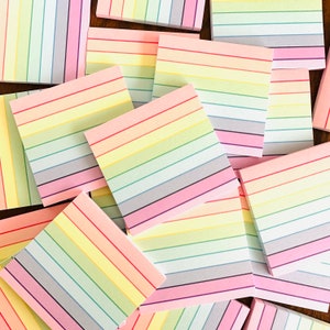 May include: A stack of colorful striped sticky notes in various shades of pink, yellow, and blue. The notes are arranged in a random pattern, with some overlapping.