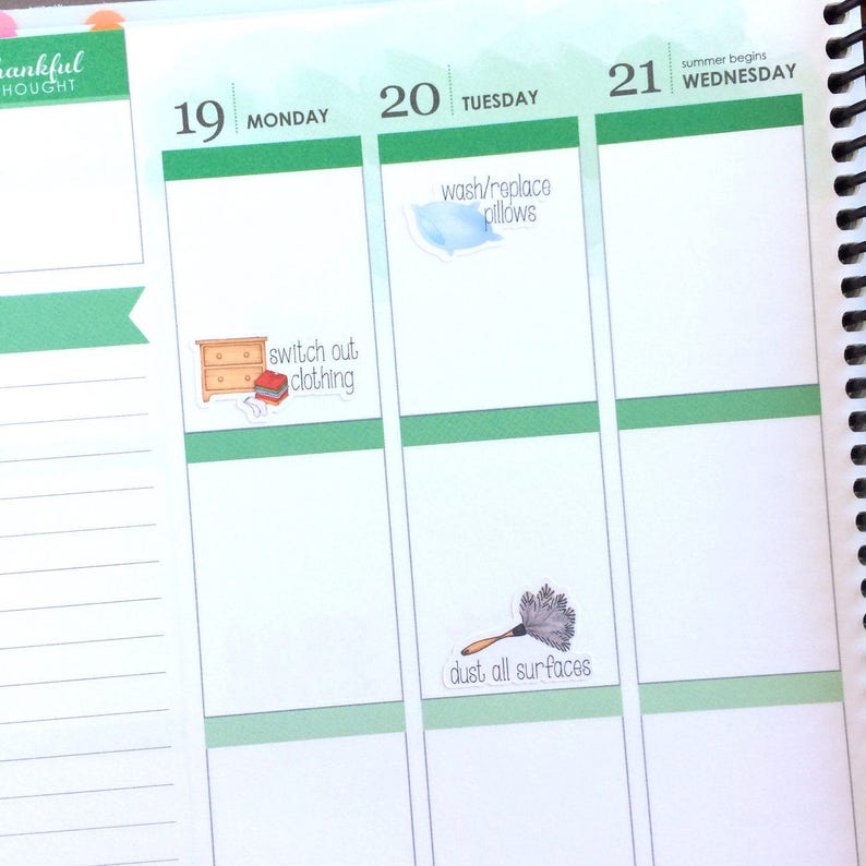 May include: A weekly planner with a green and white design. The planner has a list of chores for each day of the week. The chores include "switch out clothing", "wash/replace pillows", and "dust all surfaces".