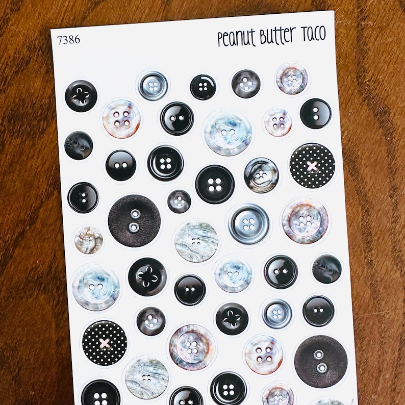 May include: Sheet of stickers featuring various button designs. The stickers include black, white, and marbled buttons, some with decorative details. The text "Peanut Butter Taco" is at the top right.