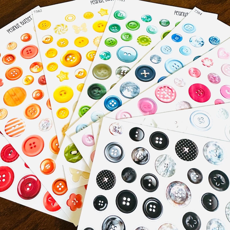 May include: Sheets of colorful button stickers in various sizes and designs. The stickers feature a range of colors, including red, orange, yellow, green, blue, pink, and black. Some buttons have striped or patterned details. The text "Peanut Butter" is visible.