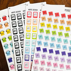 May include: Sheets of colorful planner stickers featuring book and e-reader designs, with the text "ARC" and "WRITE REVIEW". The stickers are in various colors, including red, orange, yellow, green, blue, and purple.
