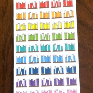 May include: A sheet of colorful book stack stickers with the text "Peanut Butter Taco" at the top. The stickers are arranged in a rainbow pattern, with red, orange, yellow, green, blue, purple, and pink book stacks.