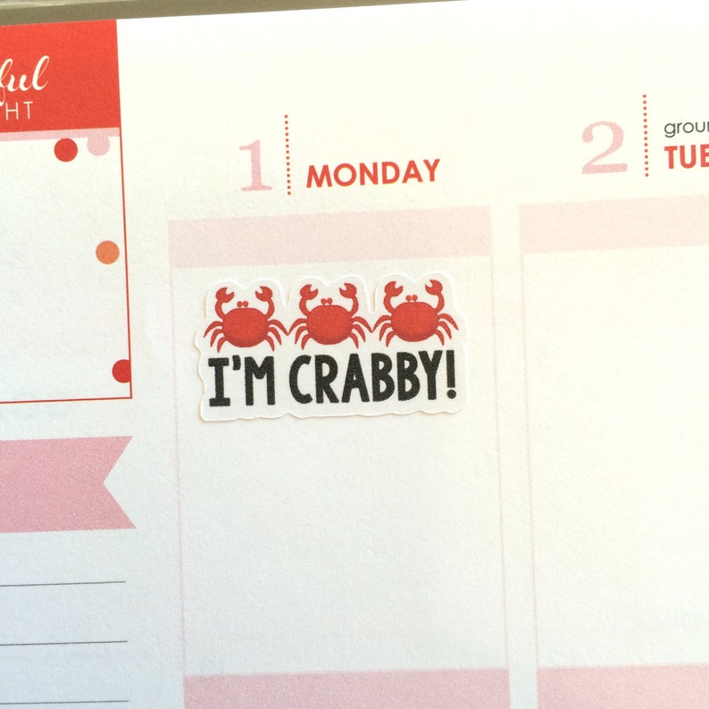 May include: Three red cartoon crabs with black eyes and claws are arranged in a row on a white sticker. The sticker has the text "I'M CRABBY!" in black letters.