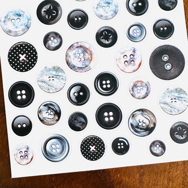 May include: A sheet of various black and white buttons. The buttons vary in size, shape, and design, including solid black, marbled, and polka dot patterns. Some buttons have two or four holes, while others have a shank.