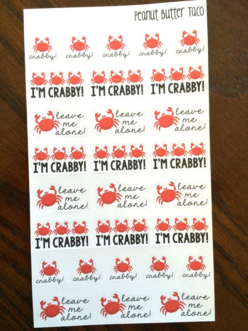 May include: A sheet of stickers featuring red crabs with various sayings, including "I'm Crabby!" and "Leave Me Alone!" The stickers are on a white background with the words "Peanut Butter Taco" at the top.