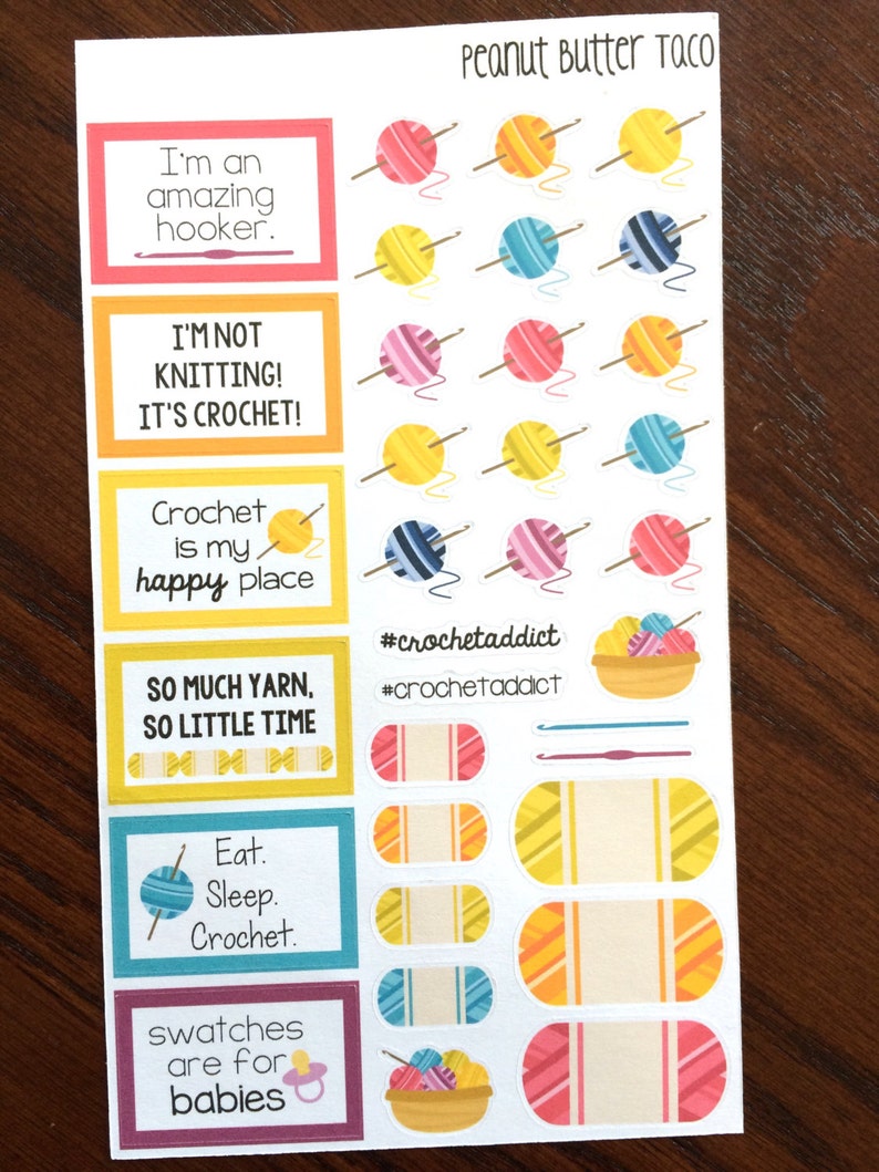 Peut inclure: Une feuille d'autocollants color&eacute;s sur le th&egrave;me du crochet. Les autocollants repr&eacute;sentent des pelotes de laine, des crochets &agrave; crochet et des phrases comme "Je suis une accro du crochet" et "Le crochet est mon havre de paix".
