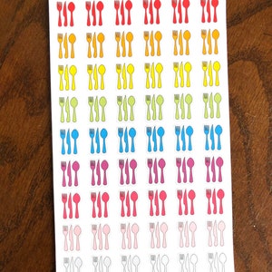May include: A sheet of stickers with a rainbow of colors featuring a fork, knife, and spoon design. The text "Peanut Butter Taco" is at the top of the sheet.