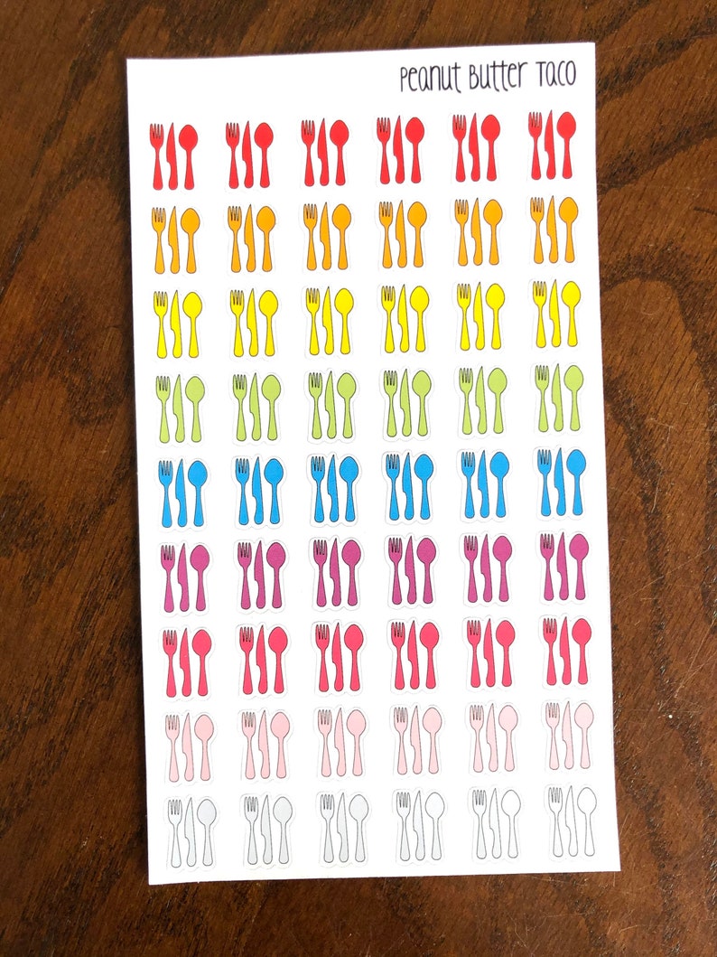 May include: A sheet of stickers with a rainbow of colors featuring a fork, knife, and spoon design. The text "Peanut Butter Taco" is at the top of the sheet.
