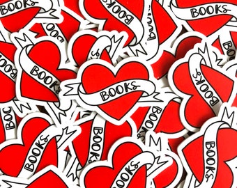 May include: A pile of red heart-shaped stickers with white outlines and black lettering. Each sticker has a banner that says "BOOKS" in a stylized font.