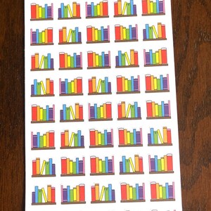 May include: Sheet of colorful book stickers with a rainbow color scheme. The stickers feature a bookshelf with a variety of books in different colors and sizes. The text "Peanut Butter Taco" is printed at the top of the sheet.