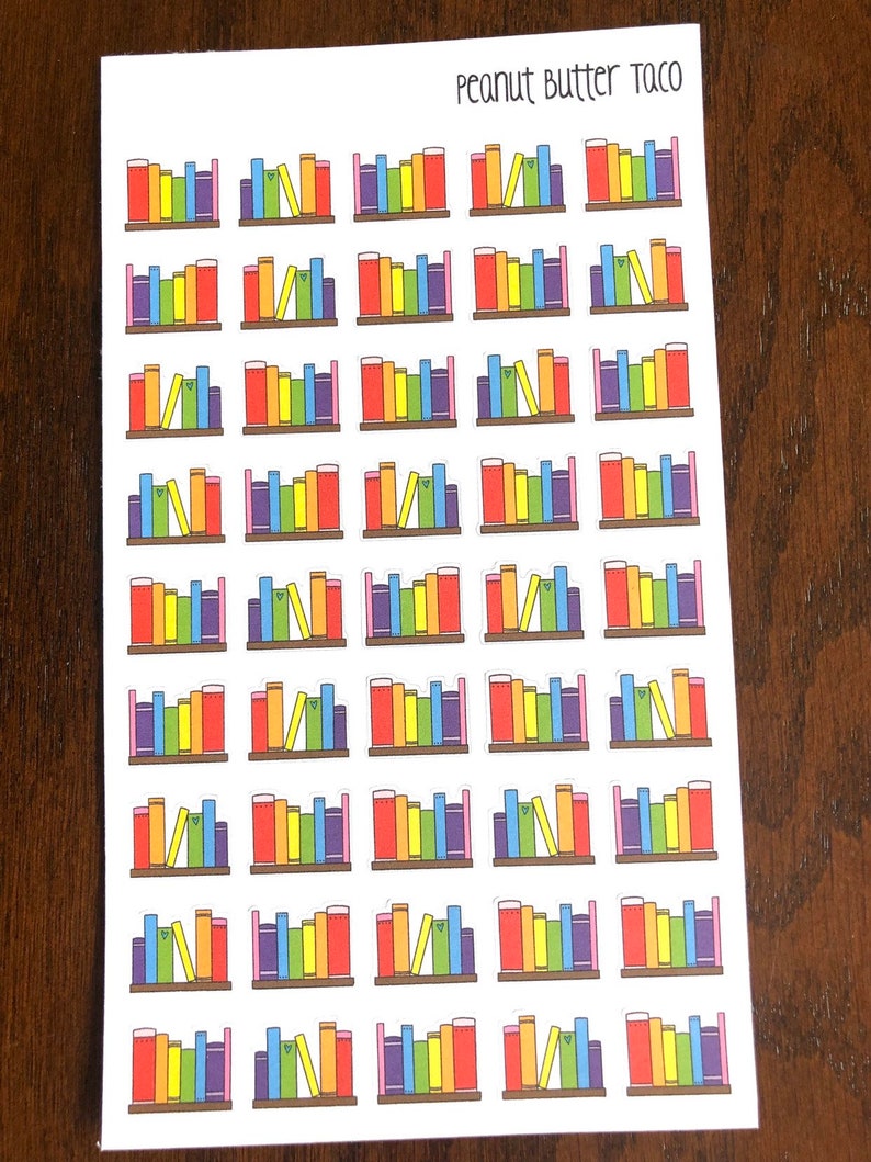 May include: Sheet of colorful book stickers with a rainbow color scheme. The stickers feature a bookshelf with a variety of books in different colors and sizes. The text "Peanut Butter Taco" is printed at the top of the sheet.