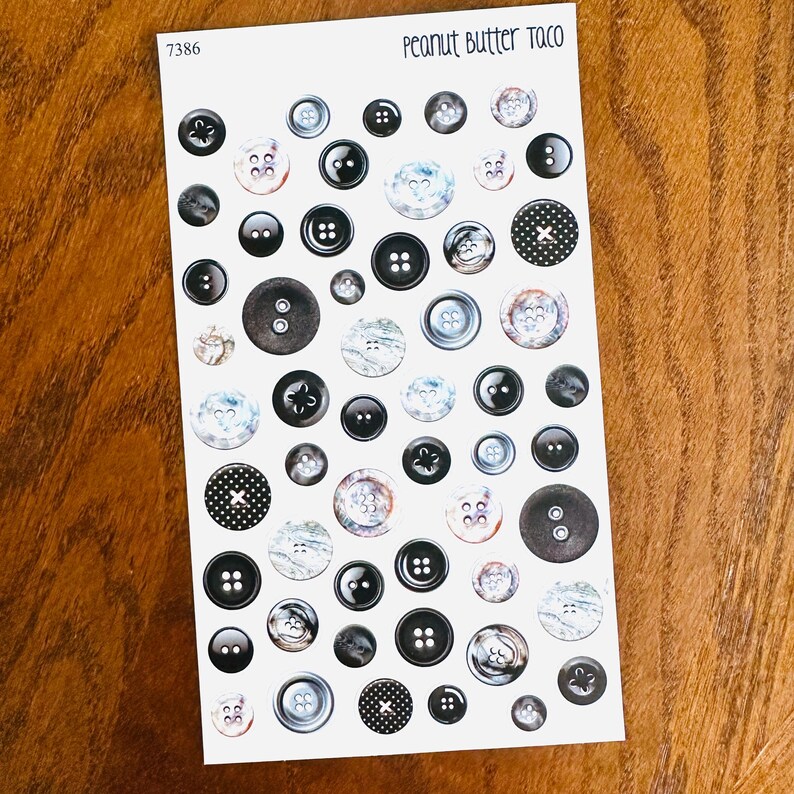 May include: A sheet of decorative buttons in various sizes and styles. The buttons are primarily black, gray, and white, with some featuring patterned designs. The text "Peanut Butter Taco" is at the top.