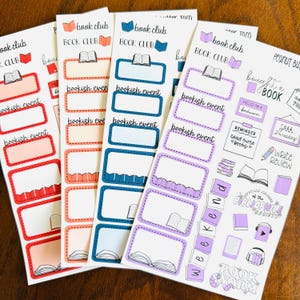May include: A collection of colorful planner stickers with a book club theme. The stickers feature rectangular labels with the words "bookish event" and illustrations of books. Additional stickers include phrases like "bought a book" and "write review."