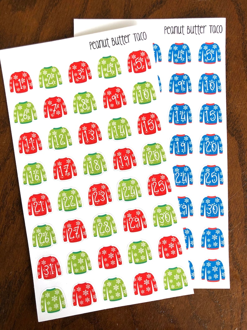 May include: Two sheets of stickers with a Christmas sweater design. The stickers are numbered 1 through 31. The sweaters are red and green with white snowflakes. The text "Peanut Butter Taco" is at the top of each sheet.