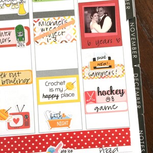 Peut inclure: Une page d'agenda avec des autocollants color&eacute;s et des notes manuscrites. Les autocollants comprennent une photo d'un couple, un crochet et de la laine, une baignoire, une crosse de hockey et un palet, et une imprimante. Les notes manuscrites comprennent "6 ans", "imprimer nouveau ! &eacute;chantillons !" et "hockey @8 jeu".
