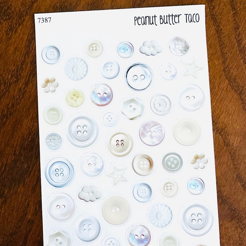 May include: A sheet of stickers featuring various white and iridescent buttons in different sizes and shapes, including stars, clouds, and flowers. The text "Peanut Butter Taco" is at the top right.