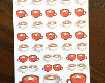May include: Sheet of stickers featuring coffee cups with heart-shaped latte art. The cups are in shades of red and white, with a brown coffee color inside. The text "Peanut Butter Taco" is at the top.