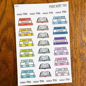 May include: A sheet of colorful stickers with illustrations of stacks of books and open books. The stickers are labeled with the months of the year and the text "make TBR".