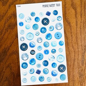 May include: A sheet of various blue buttons in different shades and sizes. Some buttons have an 'X' design, while others have multiple holes. The text "Peanut Butter Taco" is at the top, and the number "7384" is in the upper left corner.