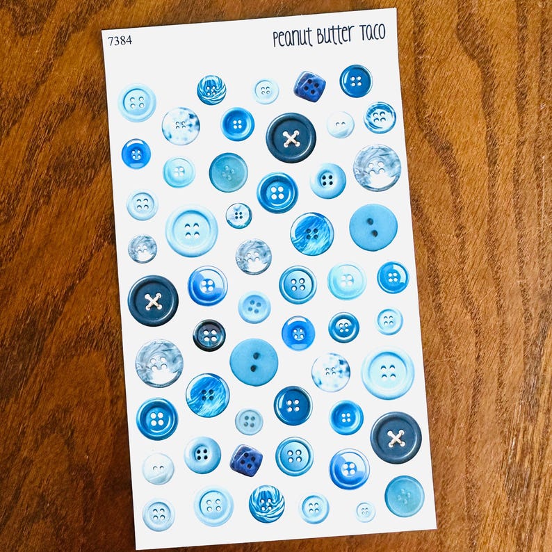 May include: A sheet of various blue buttons in different shades and sizes. Some buttons have an 'X' design, while others have multiple holes. The text "Peanut Butter Taco" is at the top, and the number "7384" is in the upper left corner.