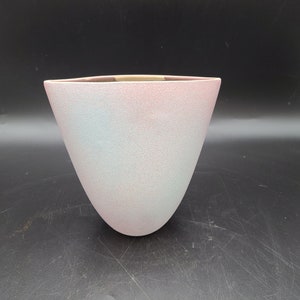 Può includere: Un vaso in ceramica rosa chiaro e blu con una superficie testurizzata.