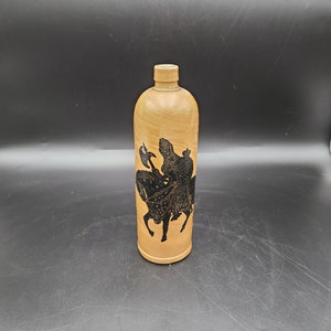 May include: A wooden bottle with a black silhouette of a person riding a horse. The bottle has a brown wood grain pattern.