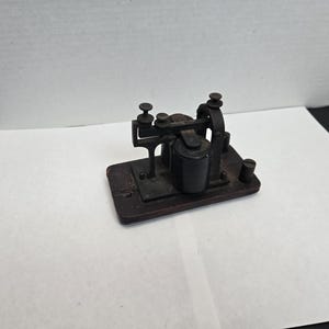 Peut inclure: Une clé télégraphique vintage en métal noir avec une base en bois. La clé a un levier et un petit cylindre en métal.