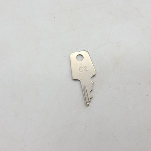 May include: A silver key with a round hole and the number 62 engraved on the top.