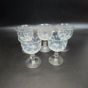 Puede incluir: Conjunto de cinco vasos de cristal transparente con tallo y diseño floral grabado.
