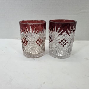 Peut inclure: Deux verres à boire assortis dotés d'un bord rouge profond et d'un corps en verre transparent. La surface extérieure est ornée d'un motif complexe en verre taillé composé de lignes entrecroisées, de motifs en étoile et d'une texture en losange.