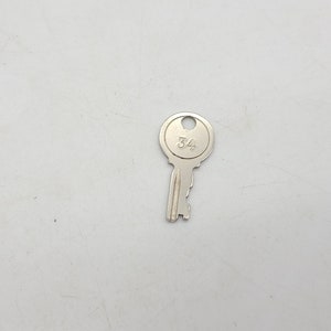 May include: A silver key with a round head and the number "34" engraved on it.