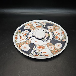 May include: A white ceramic serving platter with a removable center piece. The platter has a blue, red, and gold floral design.
