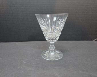 Könnte beinhalten: Ein klares, geschliffenes Weinglas aus Kristall. Es hat eine ausgestellte Schale, einen diamantgemusterten Sockel und einen schlanken Stiel. Der runde Fuß hat ein Sternmuster. Dieses Glas ist zum Servieren von Wein bestimmt.