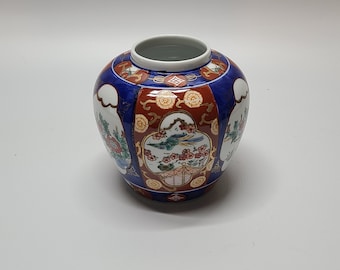 Peut inclure: Un vase en céramique bleu et rouge avec un motif floral et d'oiseaux. Le vase a un corps rond et une large ouverture.
