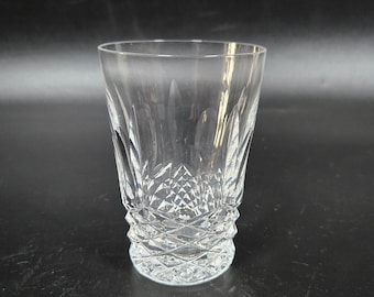 Op de afbeelding: Een heldere glazen tumbler met een geslepen kristallen ontwerp. Het glas heeft een brede opening en een ronde basis.