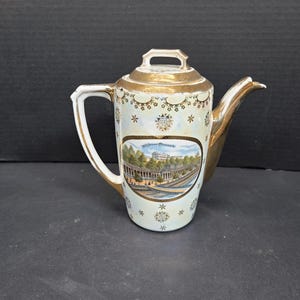 May include: Vintage porcelain teapot with gold trim and handle. The teapot features a scenic image of a building with the text "California Coronado". The teapot has a white background with floral and star patterns.