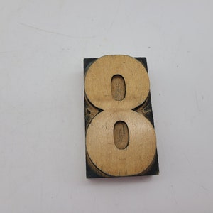 May include: A wooden number eight printing block with a black frame. The number is carved into the wood and is ready to be used for printing.