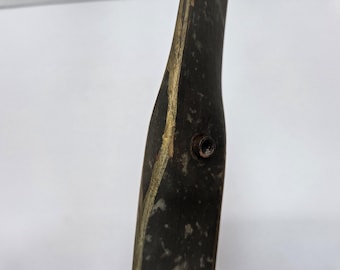 May include: Close-up of a portion of a wooden bow. The bow is dark with a gold accent and a metal screw. The bow is likely used for archery or target practice.
