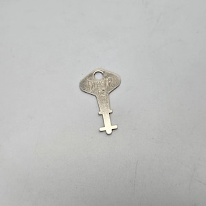 Puede incluir: Una llave de plata con la palabra "DECSOR" y el número "62" grabados en ella.