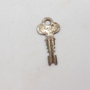 May include: A silver-toned key with a clover-shaped head. The key has a number "GH78" stamped on the head.