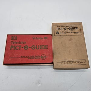 May include: A red box with the text "RCA Television Pict-O-Guide Volume III" on the front. The box is next to a brown box with the text "Here is your RCA Television Pict-O-Guide Volume III" on the front.