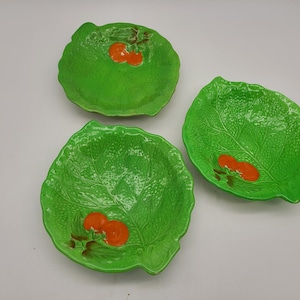 Puede incluir: Tres cuencos de cerámica verde con forma de hojas de lechuga con tomates pintados de naranja.