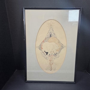 May include: Framed artwork featuring an oval-shaped image with a surreal, abstract design. The artwork has a black frame and a light-colored background. The image includes a central figure, possibly a creature, with various shapes and colors.
