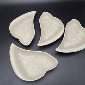 Può includere: Set di quattro piatti da portata in ceramica a forma di foglia di colore beige chiaro. Ogni piatto ha un design a foglia in rilievo.