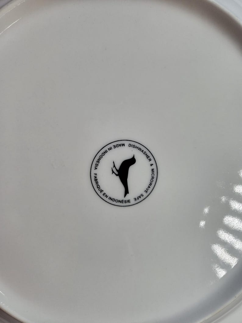 May include: White ceramic plate with a black bird logo that says "Made in Indonesia, Dishwasher & Microwave Safe"