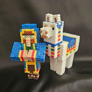Puede incluir: Una figura tridimensional de pixel art de un aldeano y una llama construida con pequeñas cuentas de plástico fusionadas. El aldeano presenta colores azul, amarillo y marrón, mientras que la llama es principalmente blanca con detalles.