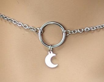 Puede incluir: Un collar choker plateado con un dije de luna creciente y un dije de anillo circular.