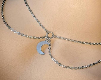 Puede incluir: Un collar de cadena de plata con un colgante de media luna. El collar está formado por dos cadenas superpuestas.