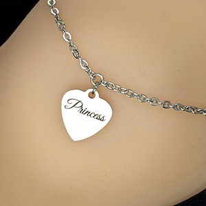 May include: A silver chain anklet with a heart-shaped pendant that says "Princess" on it.